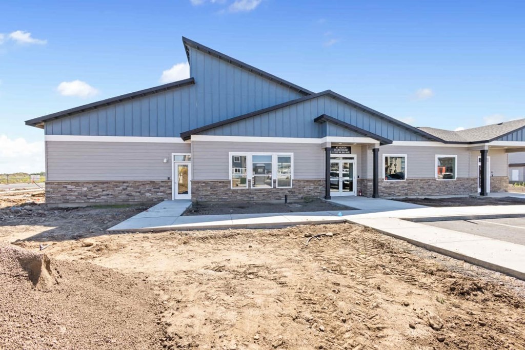 the exterior of a new building with dirt and a sidewalk