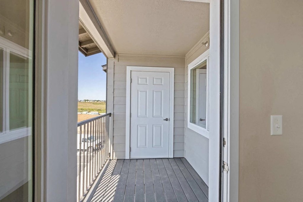 a covered porch with a white door and a balcony