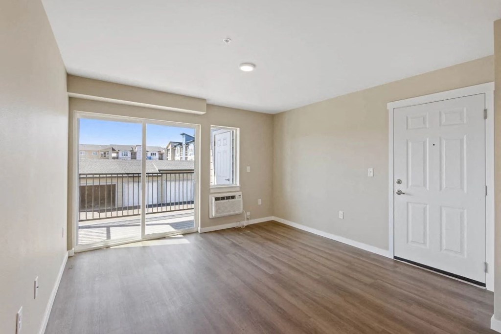 an empty living room with a door to a balcony