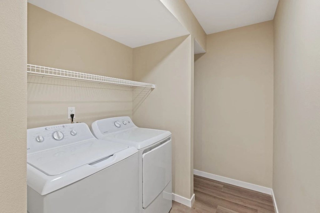 a white washer and dryer in a laundry room with a shelf above it