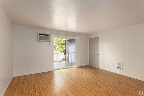 an empty living room with wood floors and a door to a balcony