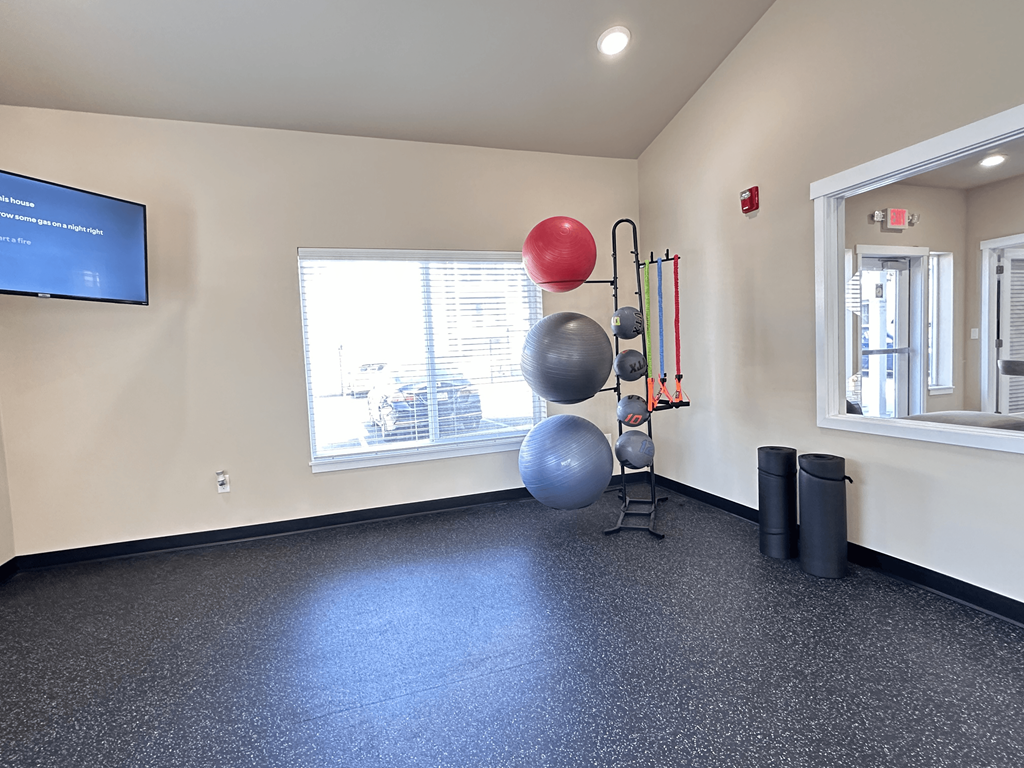 A room with a blue screen on the wall and exercise equipment.