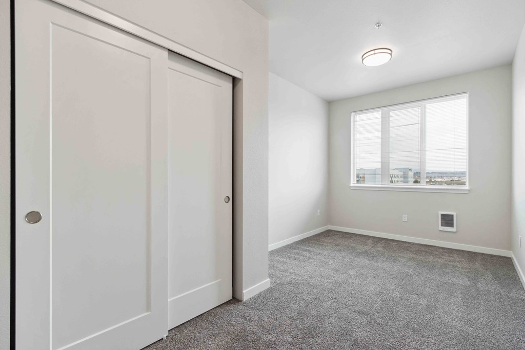 A room with a white door and a window with a view of buildings outside.