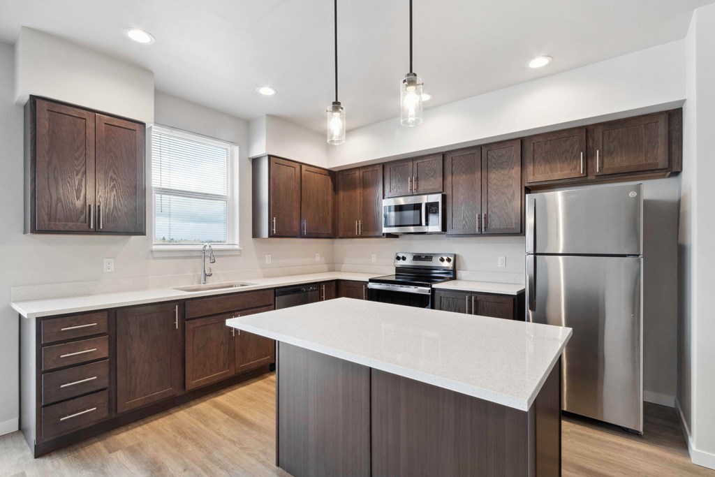 A modern kitchen with dark wood cabinets and stainless steel appliances.