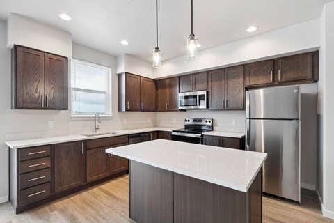 A modern kitchen with dark wood cabinets and stainless steel appliances.