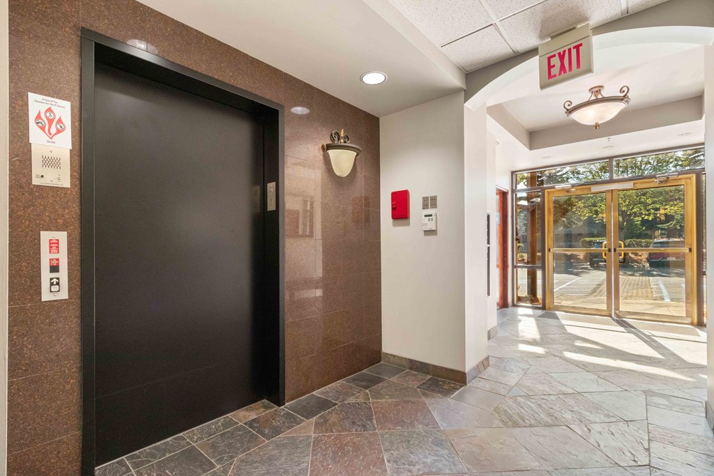 a door to a lobby with an exit sign and a glass door