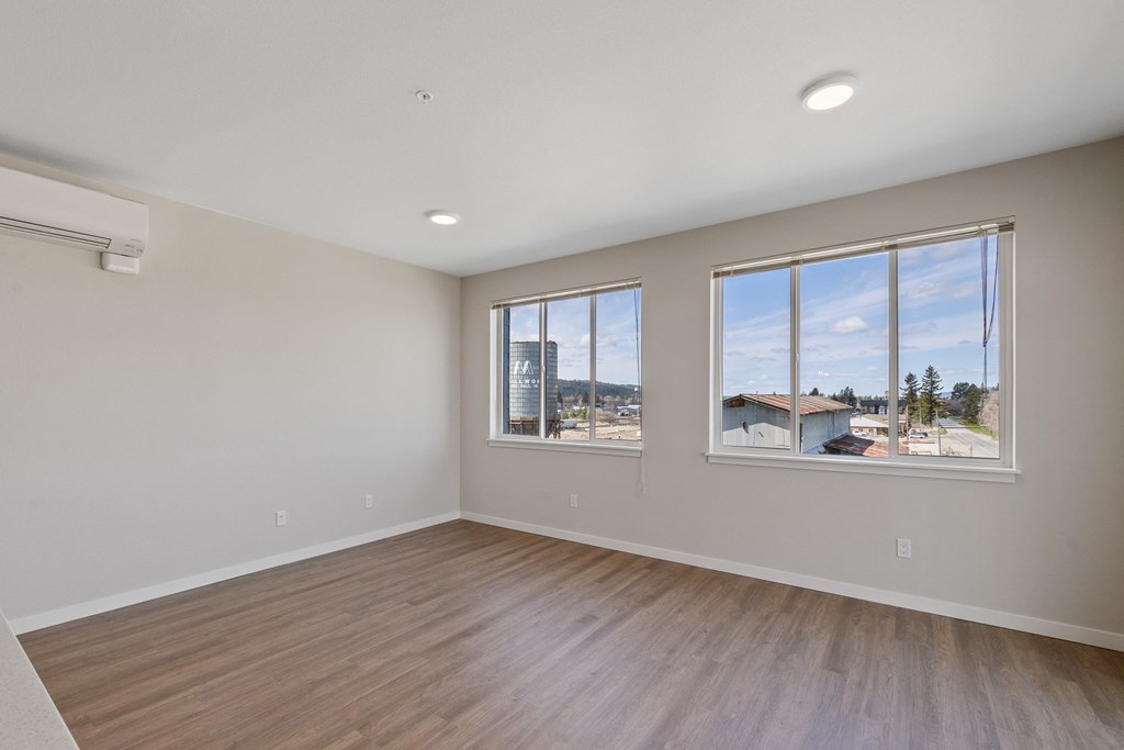 an empty living room with large windows and wood flooring