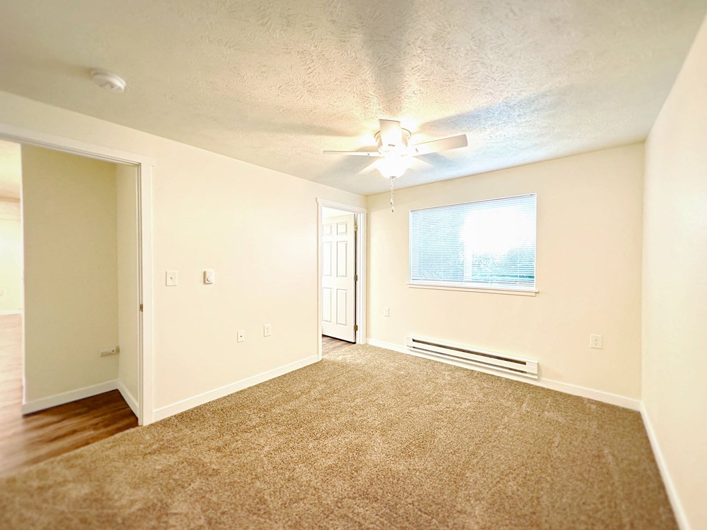 an empty living room with a ceiling fan and a window