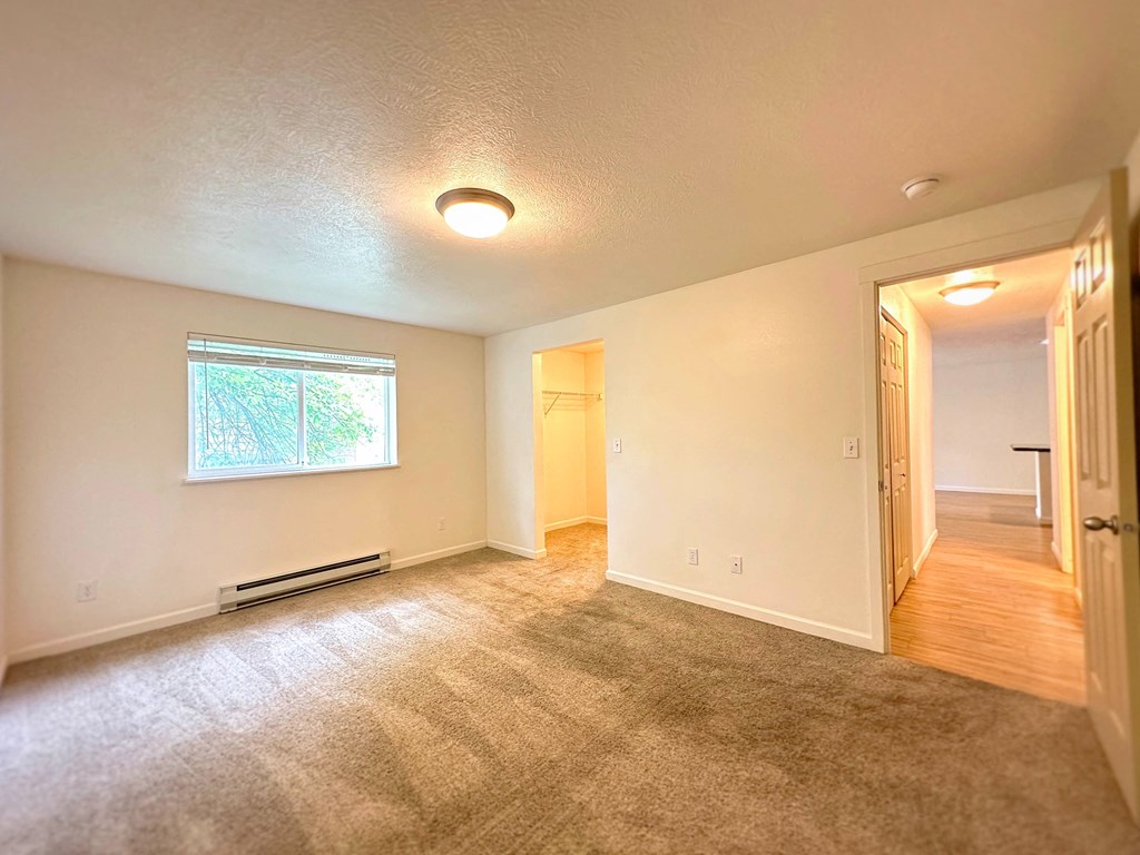 a empty living room with a window and a door to a hallway