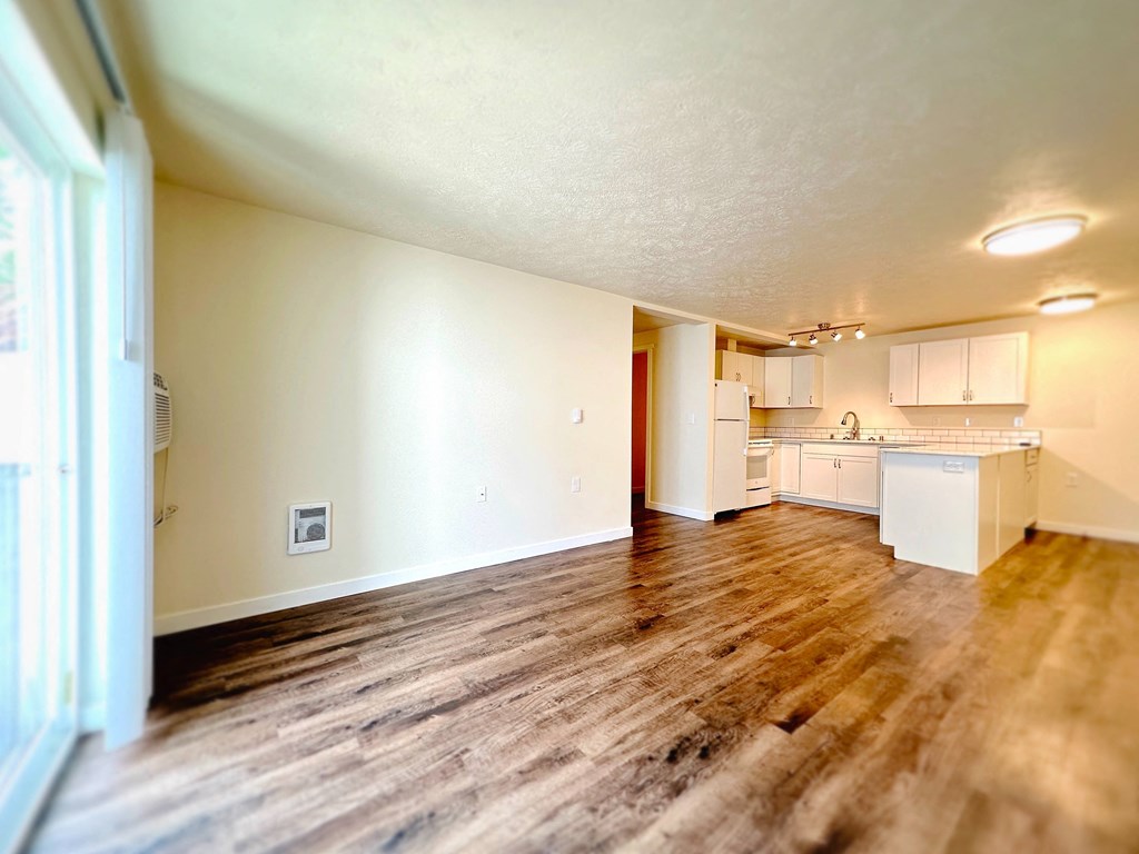 an empty living room and kitchen with wood floors