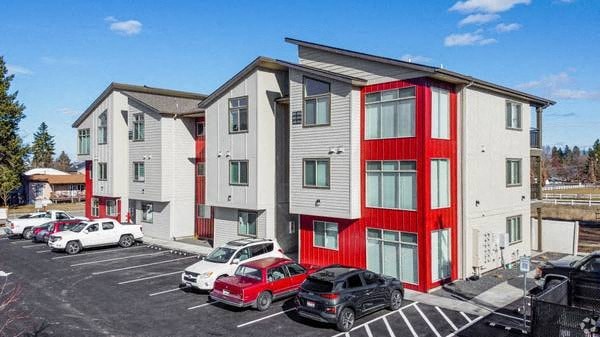 A parking lot with cars and a building with red trim.