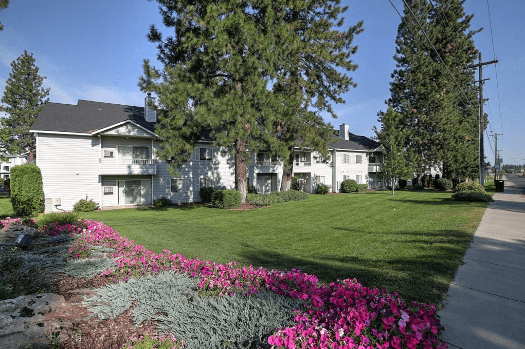 the view of an apartment building with a lawn and trees