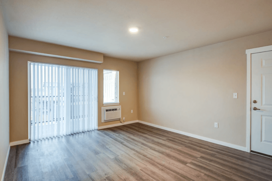 an empty living room with wood floors and a sliding glass door