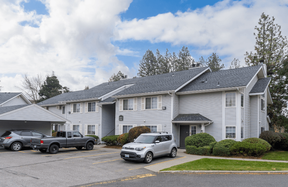 the view of an apartment building with cars parked in front of it