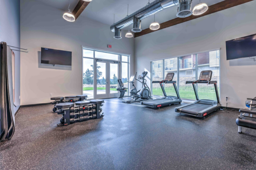 A gym with treadmills, elliptical machines, and a television.