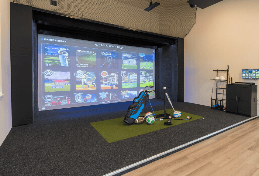 a room with a golf simulator and a projection screen