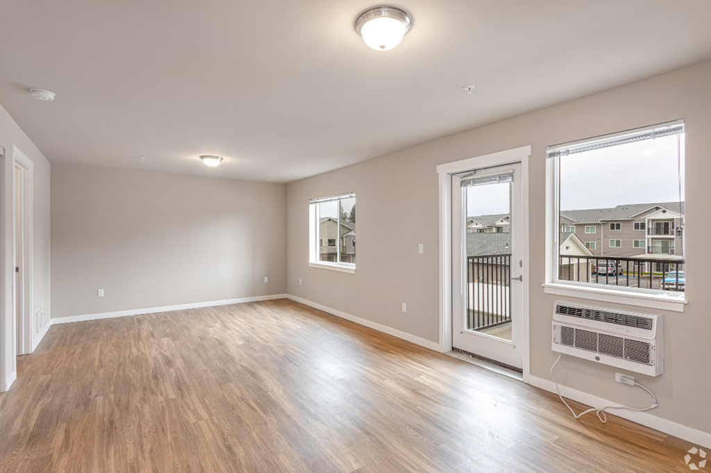 an empty living room with wood flooring and a window
