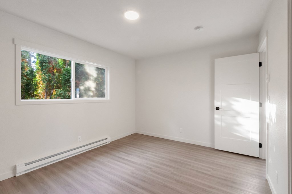 an empty room with white walls and a large window