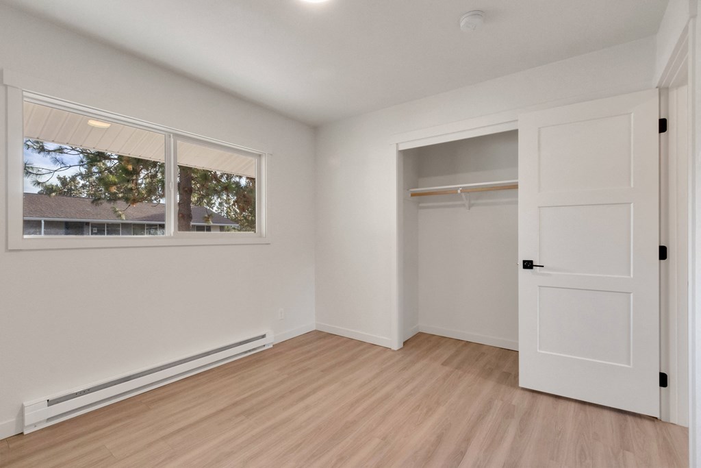 a bedroom with white walls and a white door and a window