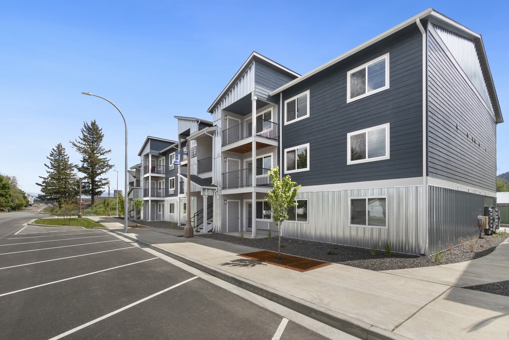 A modern apartment complex with a parking lot in front.