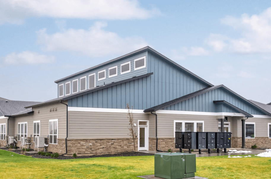 the front of the clubhouse with a blue and gray roof and a green lawn