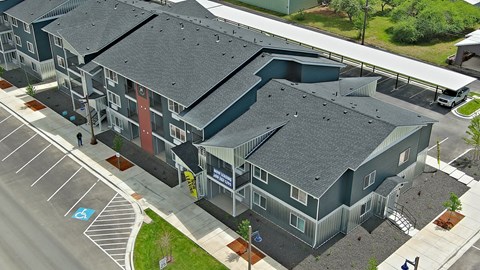 A large grey building with a parking lot in front.