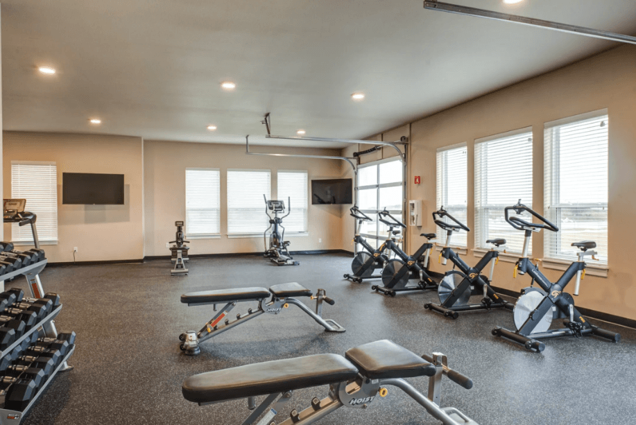 the gym has plenty of exercise equipment and windows