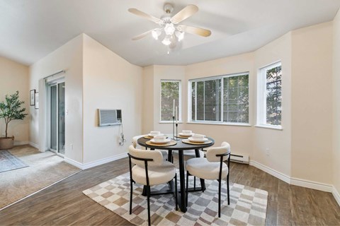A dining room with a table set for two and a ceiling fan.