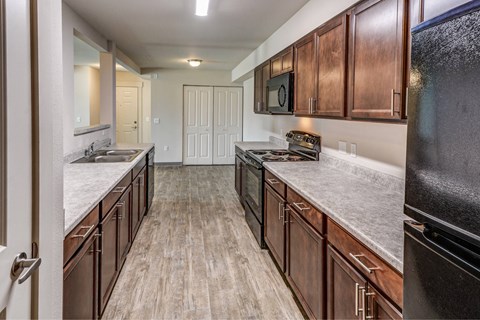 A kitchen with wood cabinets and a black refrigerator.