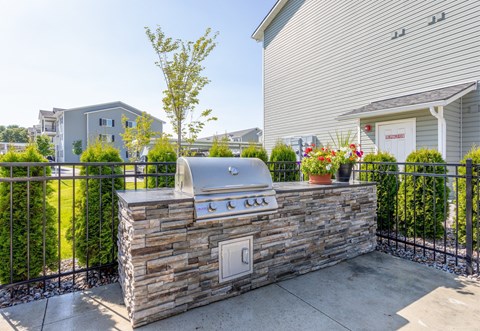 A stone wall with a grill on top and a fence in front.