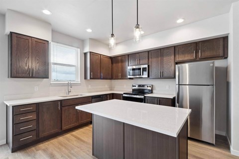 A modern kitchen with dark wood cabinets and stainless steel appliances.