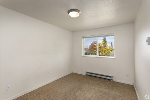 A room with a window showing trees outside.