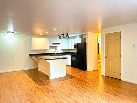 A kitchen with a black fridge and white cabinets.