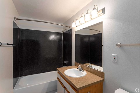 A bathroom with a sink, mirror, and shower.