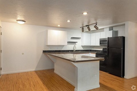 A kitchen with a black refrigerator and white cabinets.