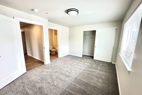 A spacious room with a carpeted floor and white walls.