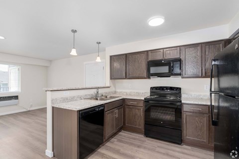 A kitchen with dark wood cabinets and black appliances.