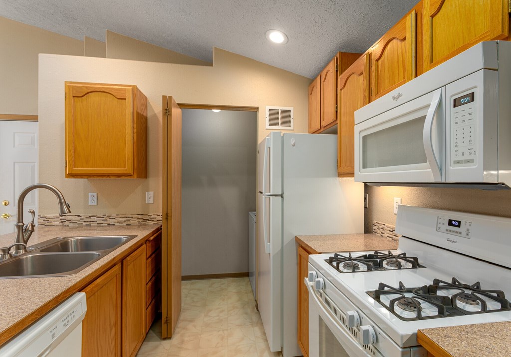 A kitchen with a stove, sink, and refrigerator.
