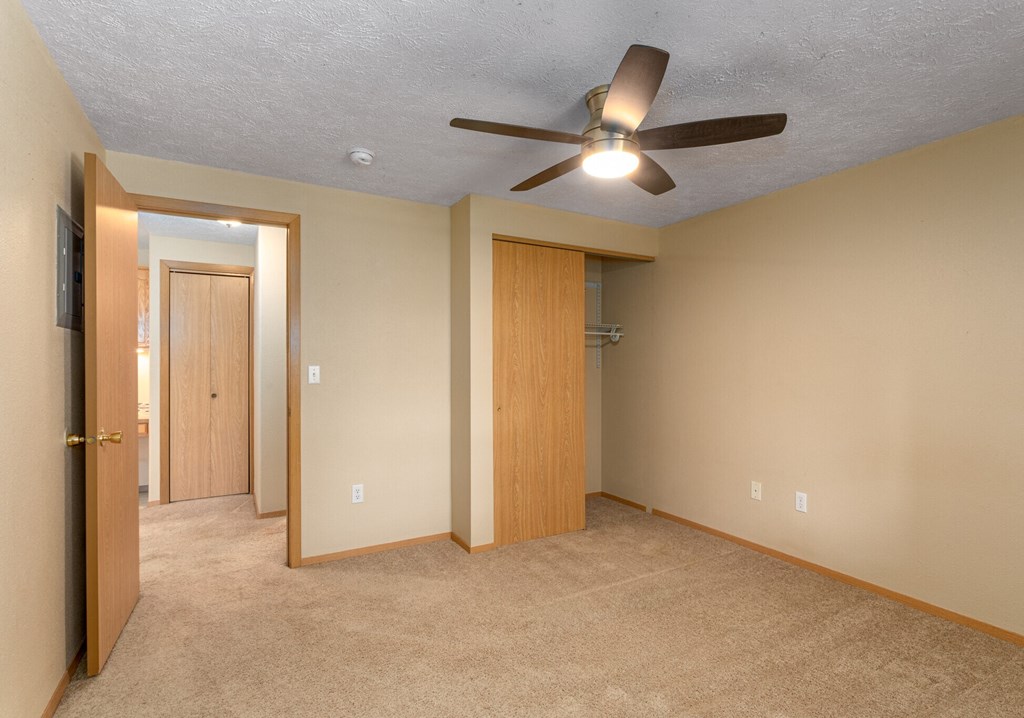A room with a ceiling fan and two doors.