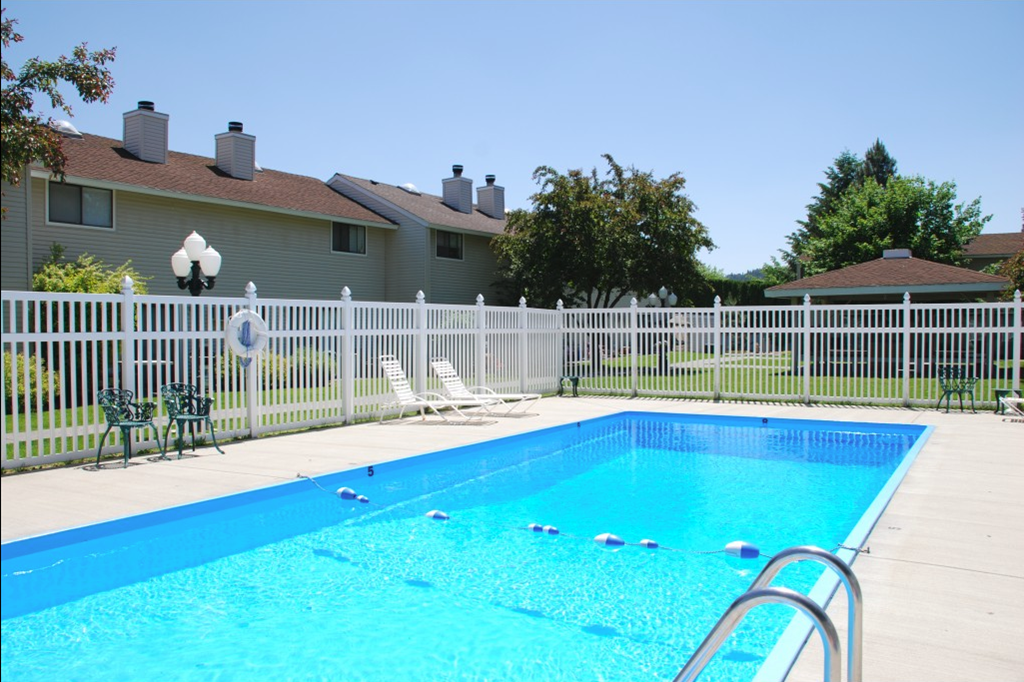 a swimming pool with a fence and a house in the background