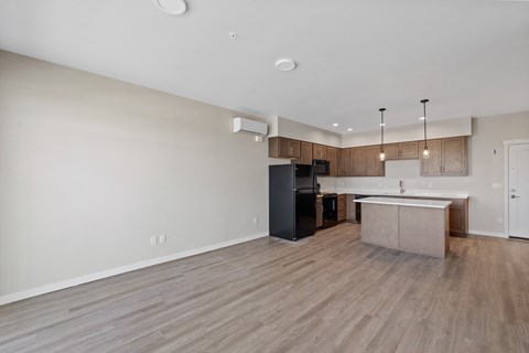 an empty living room and kitchen with wood flooring