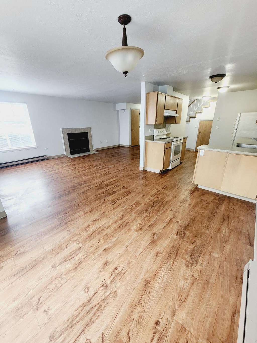 an empty living room and kitchen with wood flooring