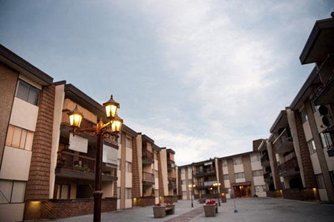 A street view of apartment buildings with a cloudy sky.