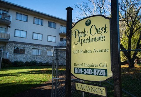A sign for Parle Crest Apartments with a phone number for rent inquiries.