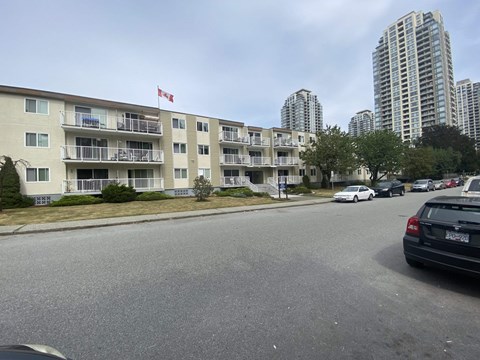A car is parked on the street in front of a building with a Canadian flag on top.