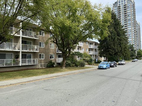 A street view of a residential area with apartment buildings and parked cars.