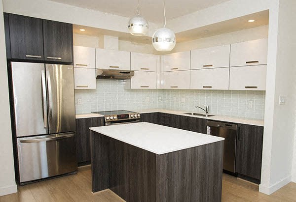 a kitchen with a white counter top and a stainless steel refrigerator