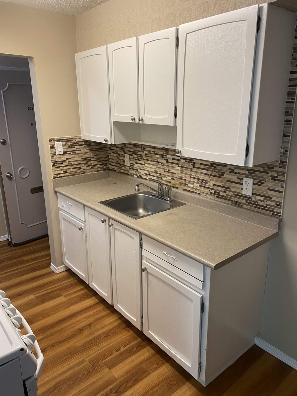 a kitchen with white cabinets and a wooden floor