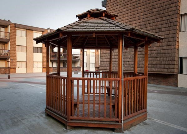 a wooden gazebo in the middle of a parking lot