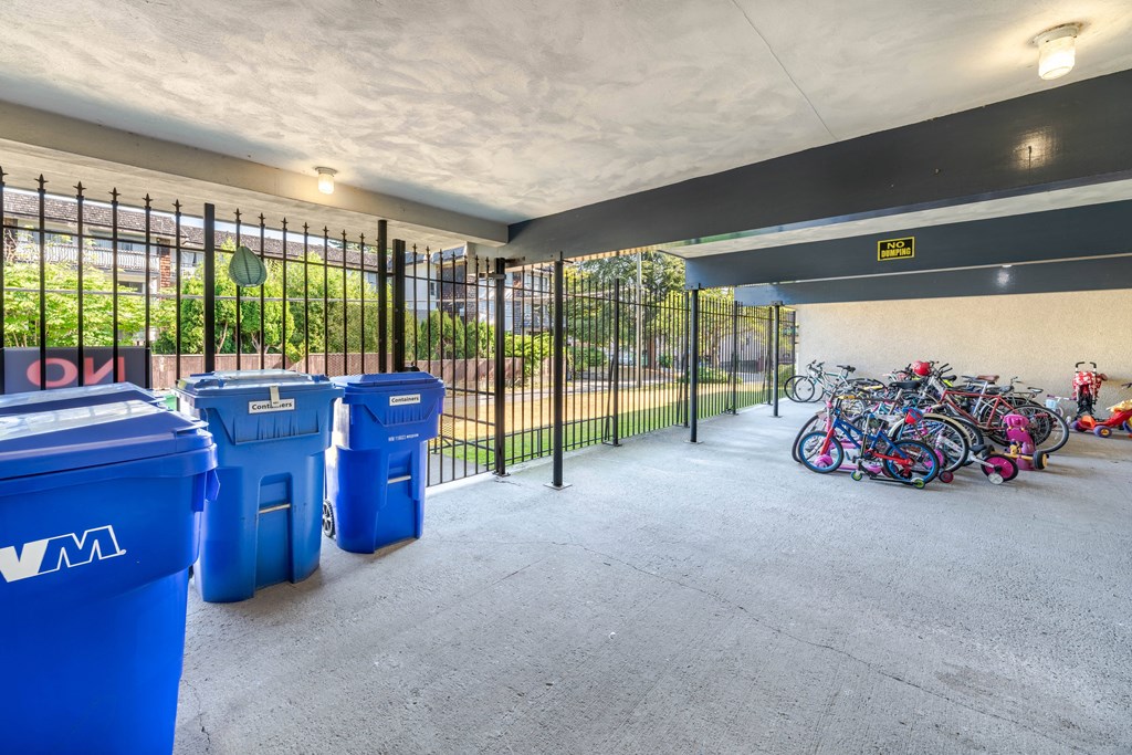 A parking garage with blue recycling bins and a yellow caution sign.